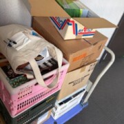 台車に積まれた段ボール箱とプラスチックカゴ、DVDや書籍をまとめた出張買取の搬出作業の様子。