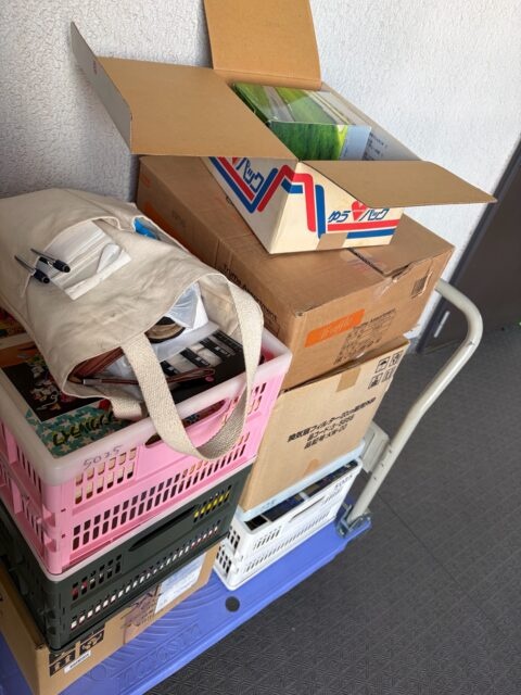 台車に積まれた段ボール箱とプラスチックカゴ、DVDや書籍をまとめた出張買取の搬出作業の様子。