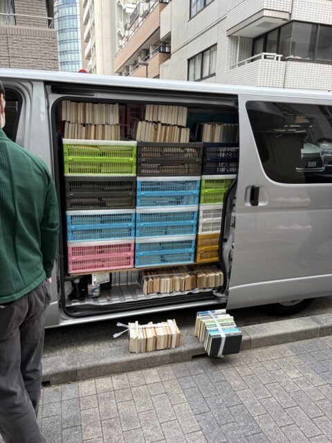千代田区神田淡路町の古本出張買取で、ハイエースの側面からコンテナに入れた書籍を積載している様子