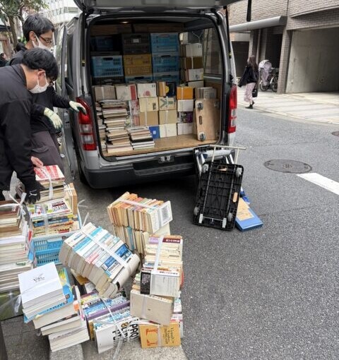 神田淡路町での古本出張買取作業中の写真。束ねた本が路上に並び、スタッフが仕分けと搬出を進めている様子