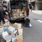 神田淡路町での古本出張買取作業中の写真。束ねた本が路上に並び、スタッフが仕分けと搬出を進めている様子