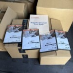 段ボール箱と投資関連DVD教材が並べられた買取品の一部。