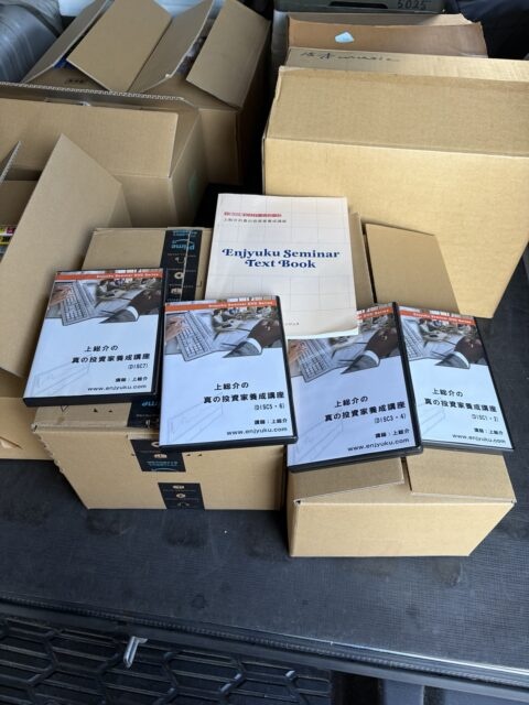 段ボール箱と投資関連DVD教材が並べられた買取品の一部。