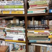 思想・哲学や専門書が並ぶ本棚と、棚の前に積み重ねられた書籍。